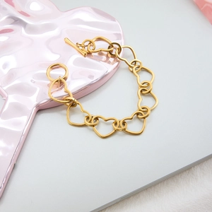 Close-up of gold heart link chain bracelet featuring a stylish OT toggle clasp design