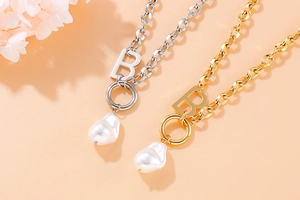 Detail of gold and silver B letter necklaces with baroque pearls and OT toggle clasps