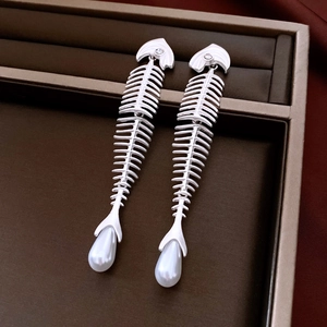 Macro shot of silver fishbone earrings with sparkling zircons and a pearl pendant