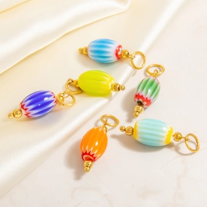 Colorful striped glass watermelon pendants with golden metal loops on beige silk