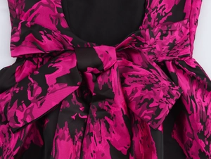 Close-up of jacquard mini dress featuring magenta floral patterns and a large back bow