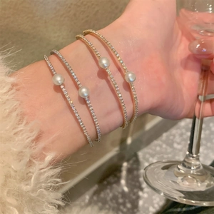 Close-up of double-layered zircon and pearl bangles in gold and silver finish