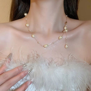 Detail shot of irregular baroque pearls on a gold chain worn on a model's neck