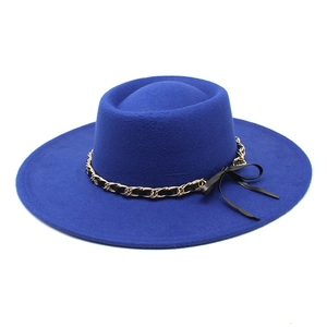 Detail of royal blue wool felt hat featuring a gold chain band and black ribbon bow