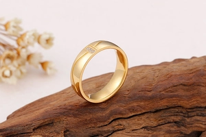 Bague en acier inoxydable doré poli avec trois zircons sur socle en bois rustique