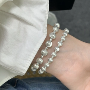 Close-up of dual stacked S925 sterling silver beaded bracelets on a woman's wrist