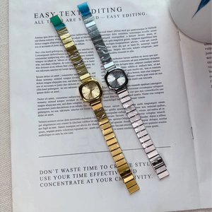 Detailed view of silver and gold square dial quartz watches with metal link bracelets