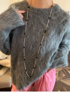 Detail of multi-layered long necklace with white pearls and black faceted gemstones