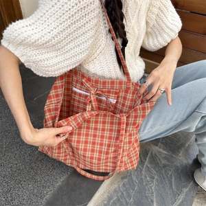 Detailed view of red plaid tote bag interior with a white zipper pocket and soft lining