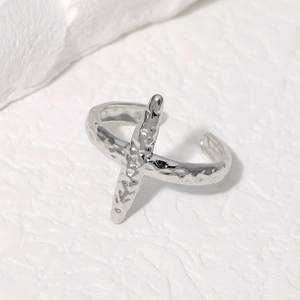 Detail of silver stainless steel ring featuring handcrafted hammered texture and cross design