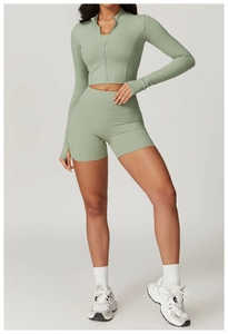 Detail of sage green yoga set showing high-waist shorts and zip-up top with thumbholes