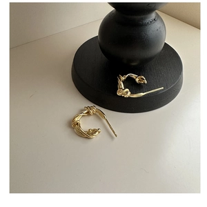 Close-up of golden S925 sterling silver twisted rope knot hoop earrings on a stand