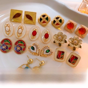 Macro shot of vintage gold-plated enamel earrings in various colors on a ceramic tray