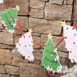 Detail of Christmas paper bunting featuring green and white trees on a red ribbon string