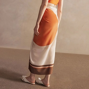 Detail of artistic orange and beige geometric split skirt with silk-like drape fabric