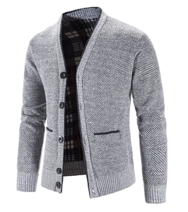 Detailaufnahme der grauen Strickjacke mit schwarz umrandeten Taschen und Karofutter-Akzent