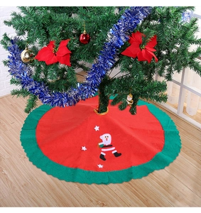 Detail of red Christmas tree skirt with green scalloped edges and Santa Claus pattern