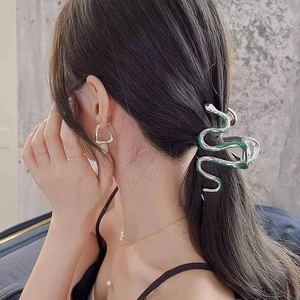 Close-up of green and silver snake-shaped metal hair claw clip worn by a model