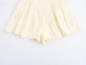 Detail of light yellow tiered ruffle dress with front buttons on white background