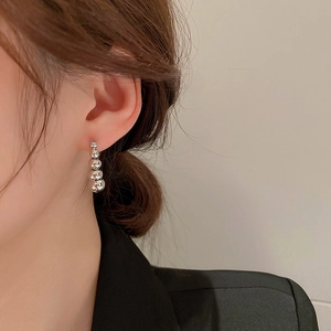Close-up of silver beaded drop earrings with four polished spheres on a female model