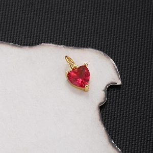 Macro shot of gold-plated red heart zircon pendant with polished metal texture