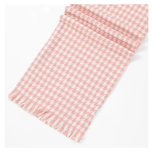 Detailed view of pink and white houndstooth cashmere scarf with soft tassel edges