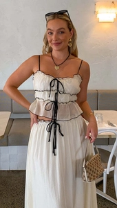 Detail of white two-piece summer set with black piping and bow tie straps on a camisole top