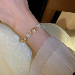 Detailed view of adjustable golden bracelet with pearls and rectangular zircon crystals
