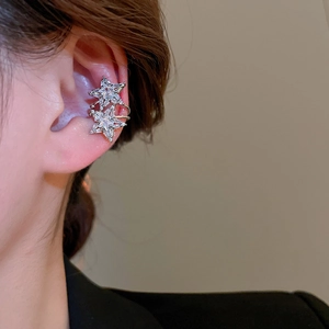 Close-up of elegant silver star ear cuff with sparkling zircons worn on ear cartilage