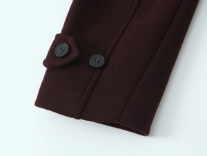 Detail of burgundy wool coat cuff with decorative black buttons and textured fabric