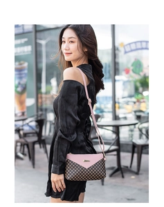 Pink flap and brown geometric pattern crossbody bag worn by a model in urban setting