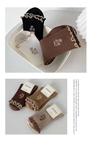 Close-up of retro ruffled cotton socks with delicate floral embroidery in earthy tones