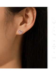 Gros plan de boucles d'oreilles cœur en émail rose avec pierres brillantes sur un modèle