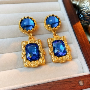 Gros plan de boucles d'oreilles vintage en or avec pierres bleues dans un écrin en velours