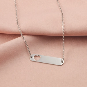 Macro view of silver hollow heart pendant necklace on pink silk fabric background