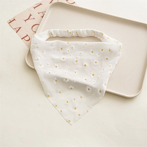 Detail of white chiffon hair tie with embroidered daisy patterns on a beige tray
