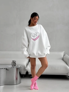Gros plan sur l'imprimé cœur rose d'un sweat-shirt blanc oversize avec texte