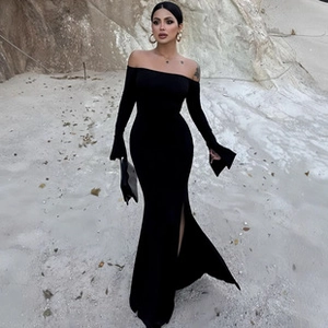 Detail of elegant black off-shoulder long sleeve dress with high side slit and slim fit