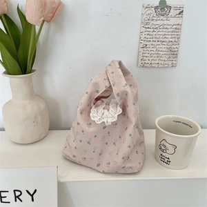 Dettaglio di borsa tote in tela floreale con pizzo bianco e motivi floreali blu