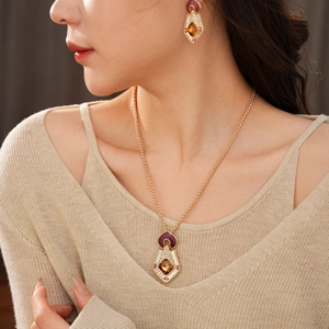 Close-up of vintage gold necklace and earrings set with purple and brown stones