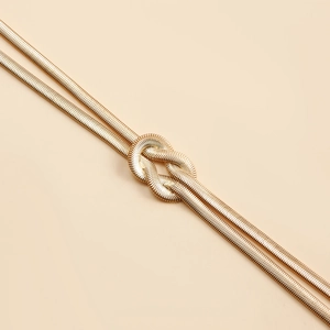 Macro shot of double gold snake chains with a decorative central knot design