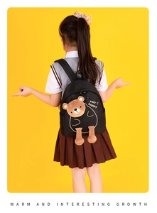 Detail view of a black preschool backpack featuring a 3D plush bear and gold patterns