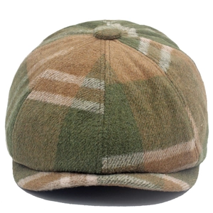 Détail d'une casquette en laine avec motif à carreaux vert olive et bouton sur le dessus