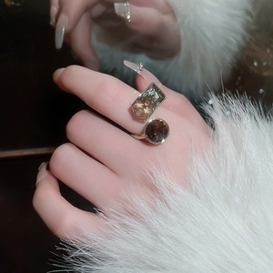 Detail of silver ring featuring amber geometric stones on hand with white fur