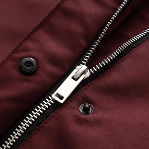 Detail of wine red coat featuring a metallic zipper and black star-embossed snap buttons