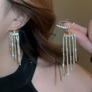 Detail of long gold tassel earrings with crystal heart bow on model with a warm glow