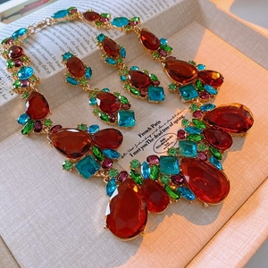 Detail of vintage gold jewelry set with colorful teardrop crystals and stud earrings
