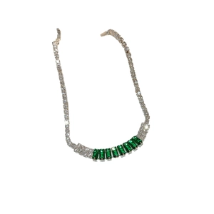 Luxurious silver bracelet featuring white round diamonds and green emerald-cut cubic zirconia