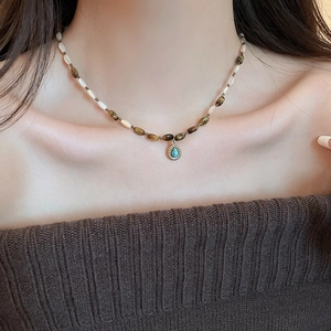 Macro view of teardrop turquoise pendant with beaded tiger eye and shell stone necklace