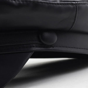 Macro view of black faux leather texture and precise stitching on the vintage newsboy cap